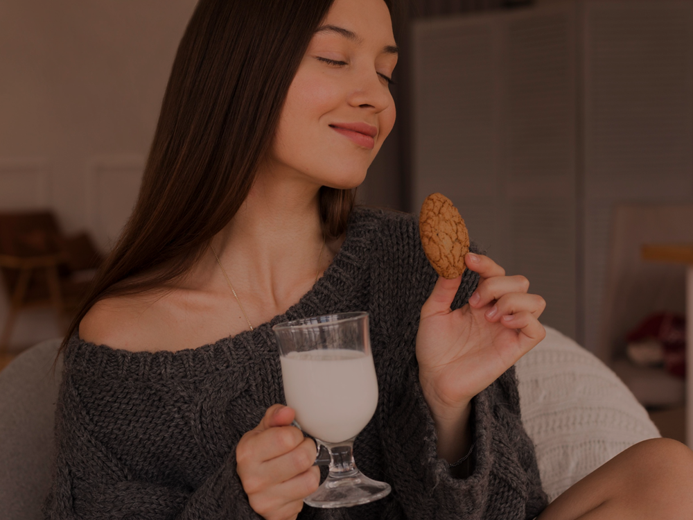 Fotografia ilustrativa de uma moça com um copo de leite e um biscoito nas mãos. - Smoothie de café com chocolate