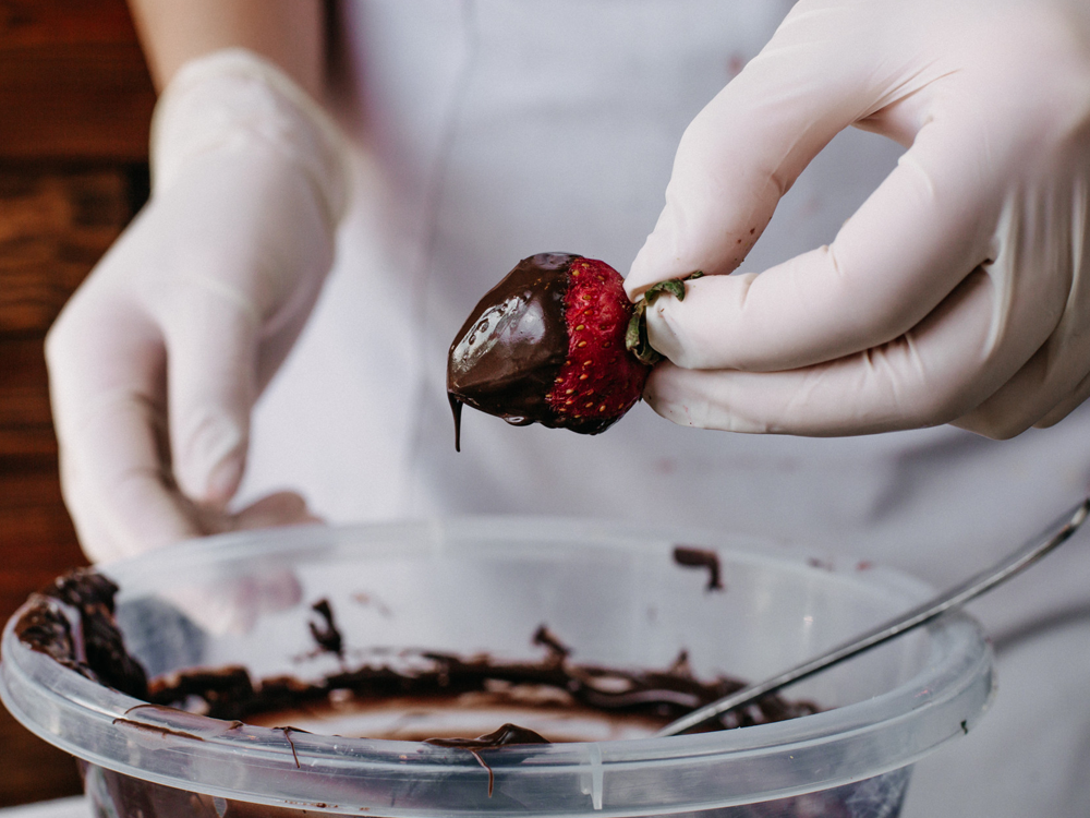 Fotografia ilustrativa morango sendo banhado de chocolate de cacau recheada